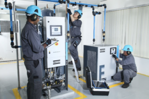 Three employees carrying out maintenance on an air compressor